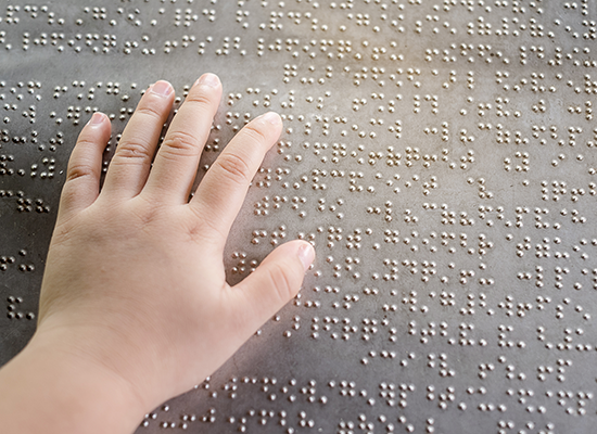 Child's hand reading braille Shutterstock